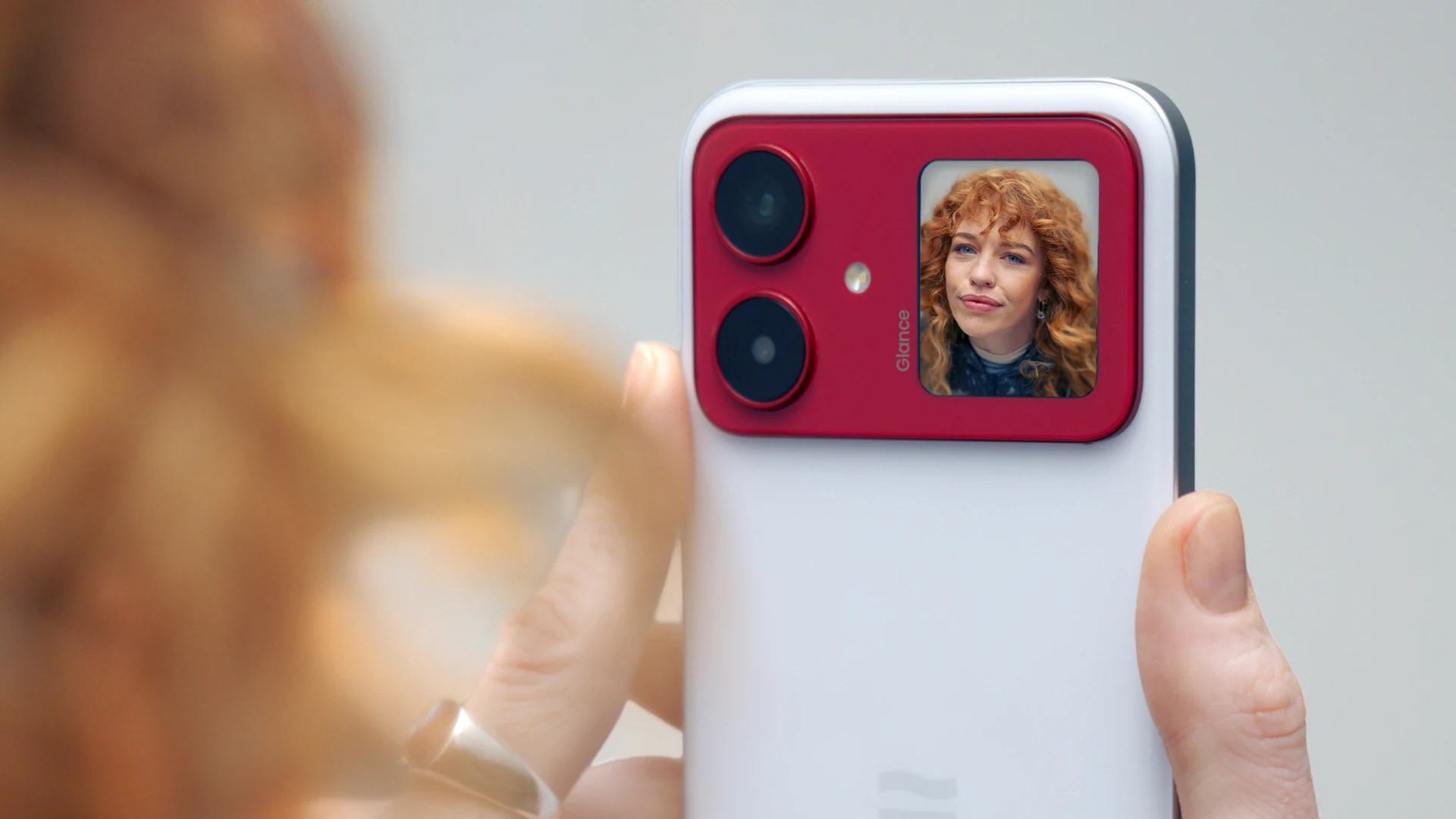 Holding the LoopPhone to frame a subject — the Glance Display acting as a live viewfinder for the 200MP main camera
